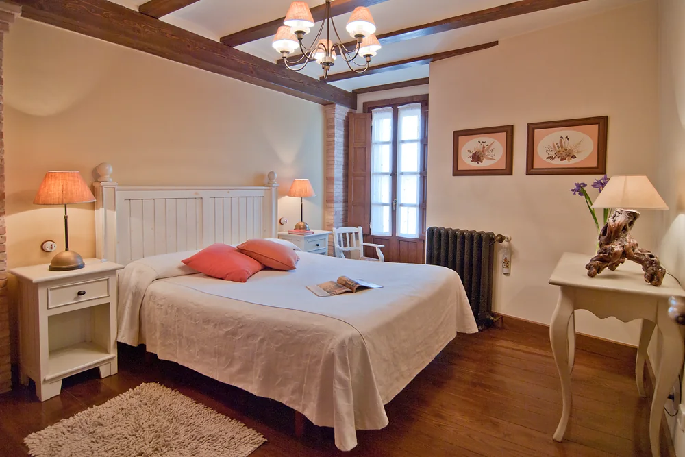Dormitorio con cama de matrimonio y techo de vigas de madera
